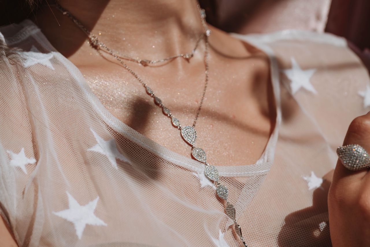 faq-img Close-up of a stylish diamond necklace on a star-patterned sheer fabric, capturing elegance.